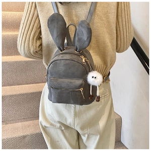 Détail du sac à dos gris foncé avec oreilles de lapin et charme en peluche