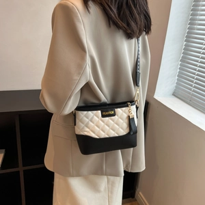 Detail of quilted diamond pattern bag with wide jacquard strap and gold tassel accent