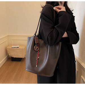 Gros plan d'un sac cabas en cuir marron vintage avec des breloques chocolat et bretzel
