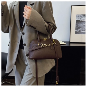 Detail of dark brown leather shell bag with gold hardware and removable shoulder strap