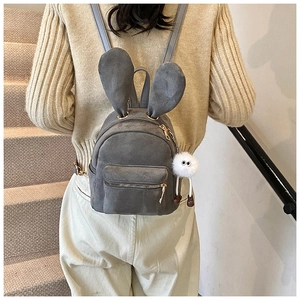 Gros plan d'un mini sac à dos gris avec oreilles de lapin et pompon blanc sur un modèle