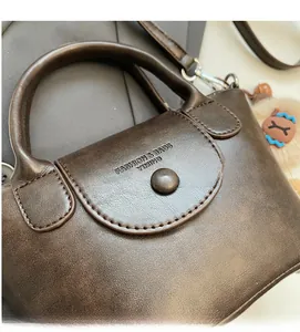 Close-up of a vintage brown leather handbag with textured flap and decorative buckle