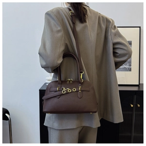 Detail view of a vintage dark brown shell bag styled with a grey oversized suit jacket