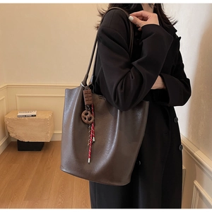 Détail d'un grand sac cabas marron foncé avec breloque chocolat porté à l'épaule