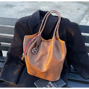 Détail du sac seau marron vintage avec breloques uniques sur une surface texturée