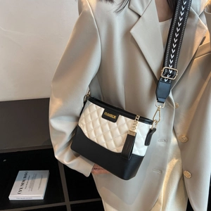 Detail view of black and white quilted shoulder bag with patterned strap and gold hardware