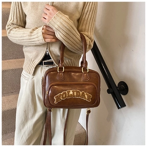 Close-up of retro brown bowling bag featuring plush HOLIDAY lettering and gold hardware