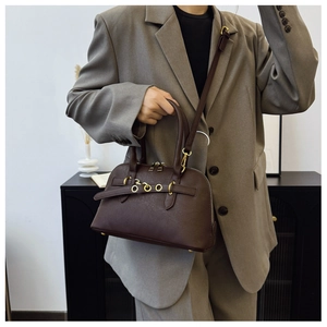 Detail of vintage dark brown pebbled leather shell bag with gold rings and adjustable strap