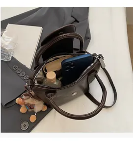 Top view of the spacious inner compartment of a vintage crossbody bag with a plush charm