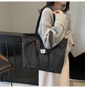 Detail view of a large dark grey canvas tote bag with a white minimalist fabric label