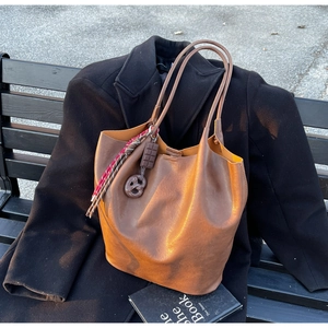Détail d'un sac cabas en cuir marron orné de charms originaux en forme de bretzel et chocolat
