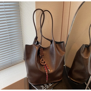 Gros plan d'un sac seau en cuir marron foncé avec un nœud décoratif et un pompon coloré