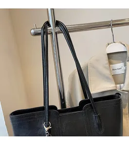 Detail of black pebbled leather tote bag with silver hardware and dual shoulder straps