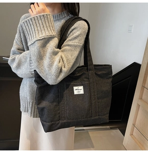 Detail of large denim tote bag featuring workwear style woven label on the front
