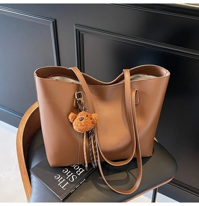 Détail du sac cabas marron en similicuir avec fines bandoulières et pendentif ours