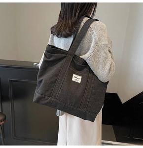 Macro shot of large black denim tote bag with white woven label showing stitching details