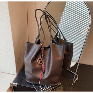 Détail d'un sac cabas en cuir marron foncé avec charm bretzel et accent de corde tressée