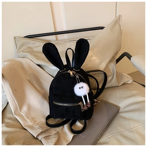 Détail d'un mini sac à dos en velours noir avec oreilles de lapin et peluche sur un canapé