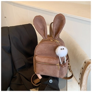 Détail du sac à dos marron en similicuir avec oreilles de lapin et charm peluche monstre