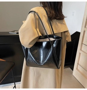 Dettaglio della borsa tote nera lucida con logo in rilievo e sottili spalline