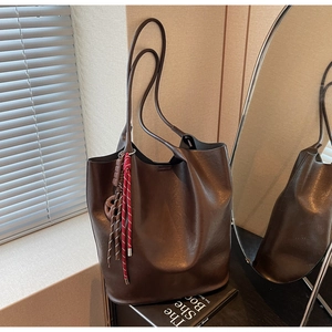 Gros plan d'un grand sac seau marron foncé avec un charme décoratif en corde tressée