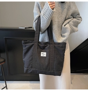 Macro detail of large denim tote bag featuring side pocket and white square patch
