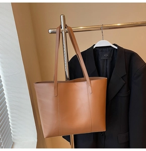 Détail du sac cabas en cuir marron avec des poignées renforcées et une finition mate