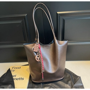 Détail du sac fourre-tout en cuir marron avec des breloques chocolat et bretzel
