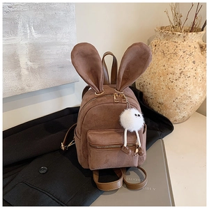 Détails d'un mini sac à dos en daim marron avec oreilles de lapin et charm peluche