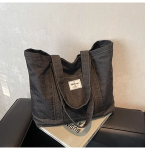 Detailed view of the dark denim tote bag with white logo patch and contrast stitching
