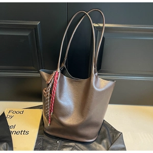 Détail du cabas en cuir mat marron avec pompon décoratif tissé rouge et blanc élégant