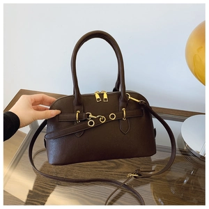 Detail of dark brown shell bag with smooth grain texture and gold zipper hardware