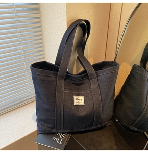 Detailed side view of dark blue denim tote bag showing Hbag logo and fabric texture