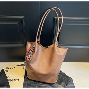 Détail du sac cabas en cuir marron foncé avec pendentif en corde tressée et fines anses