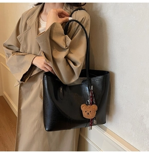 Large black vintage tote bag with bear charm detail on a model in a trench coat