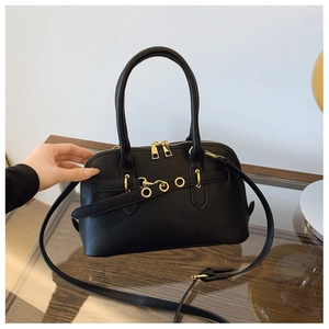 Detail of black leather shell bag with gold hardware and removable shoulder strap