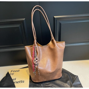 Détail du sac seau en cuir marron avec breloque en forme de bretzel et cordon tressé