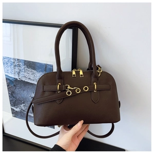 Detail of dark brown shell-shaped handbag with pebbled texture and gold hardware details