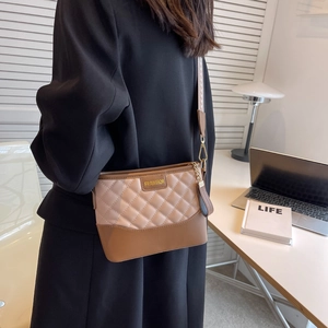 Detail view of beige and brown quilted crossbody bag with ethnic print strap