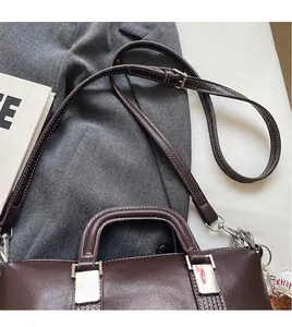 Détail du sac Boston marron foncé avec surpiqûres contrastées et ferrures en métal argenté