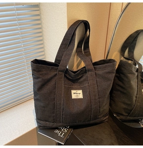Detail of blue denim tote bag with white label and functional front pocket design