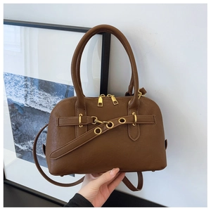Detail of classic brown handbag showing gold metal rings and dual-zipper closure