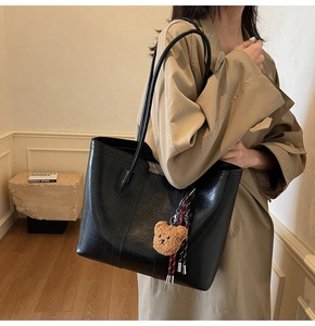 Classic large black tote bag featuring a cute brown teddy bear charm and tassel details