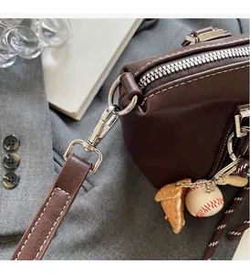 Détail d'un sac à main en cuir marron foncé avec ferrures argentées et porte-clés baseball