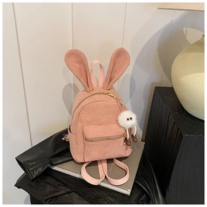 Détail d'un mini sac à dos en daim rose avec oreilles de lapin et porte-clés monstre en peluche