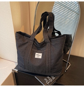 Close-up of deep gray denim tote bag featuring sturdy stitching and brand label detail