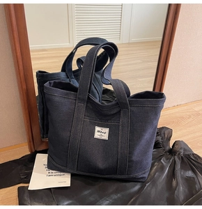 Detailed close-up of dark denim tote bag with Hbbag logo patch and reinforced handles