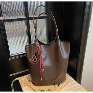 Gros plan d'un grand sac cabas marron avec charm bretzel et corde tressée sur table en marbre