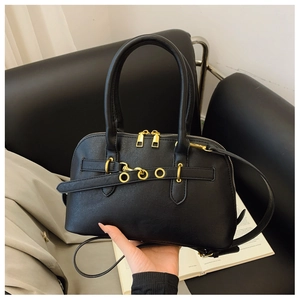 Detail of vintage black leather shell bag with gold hardware and dual zipper closure