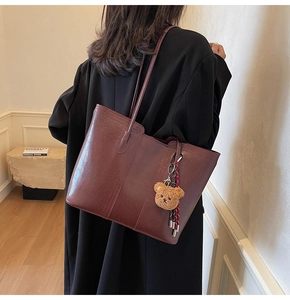Deep burgundy large tote bag with bear charm detail shown on model in modern setting